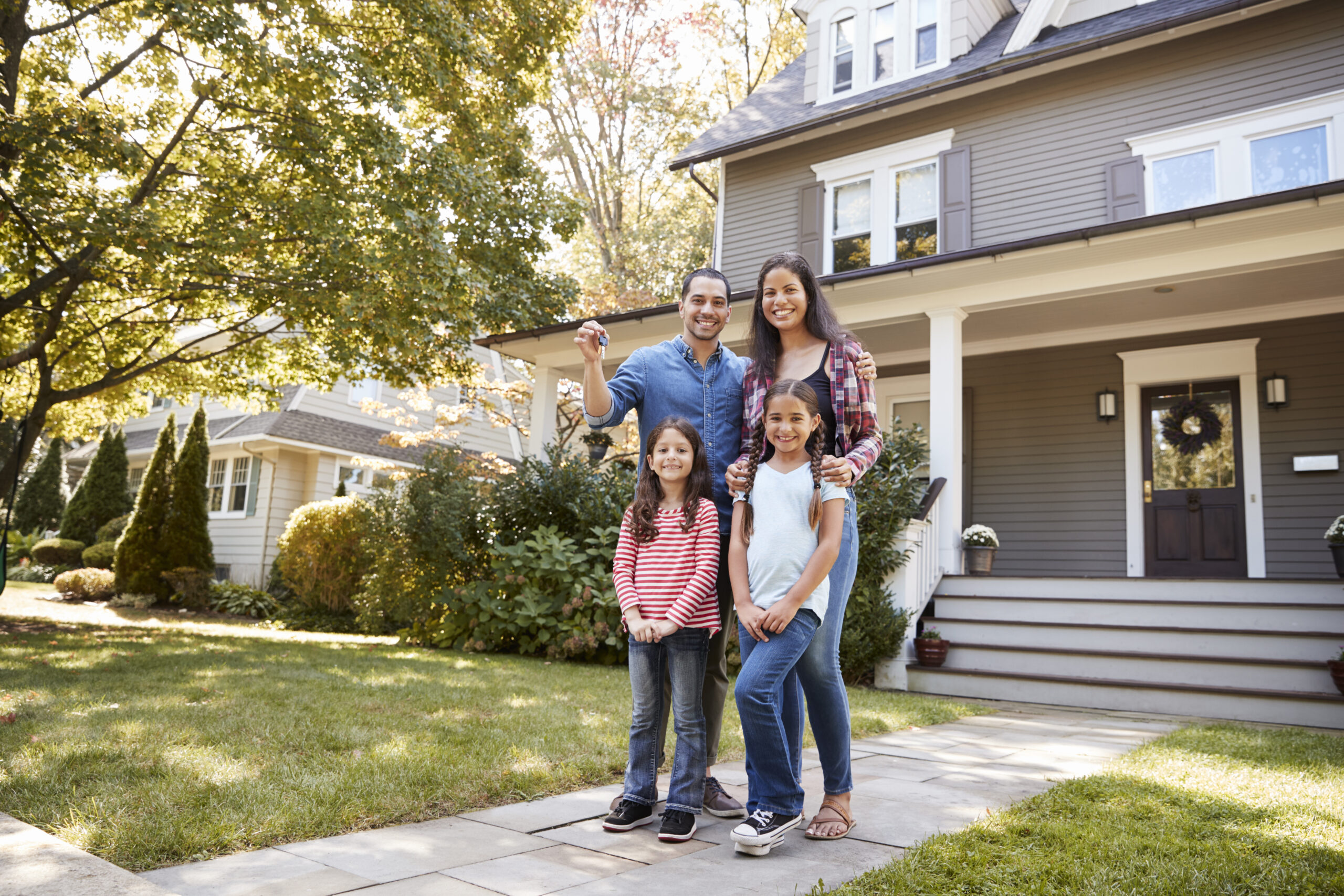 portrait of family holding keys to new home on moving in day